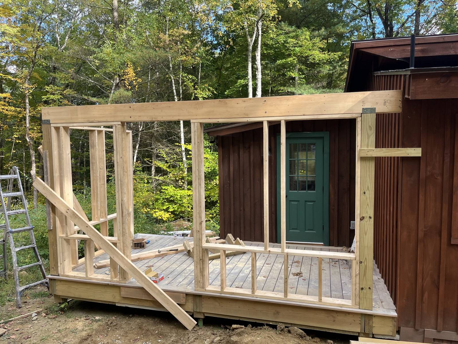 Timber-framed addition walls standing against a cedar camp in the woods